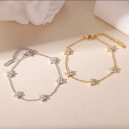 Gold and silver bracelets with clear gemstone floral design on a biege background
