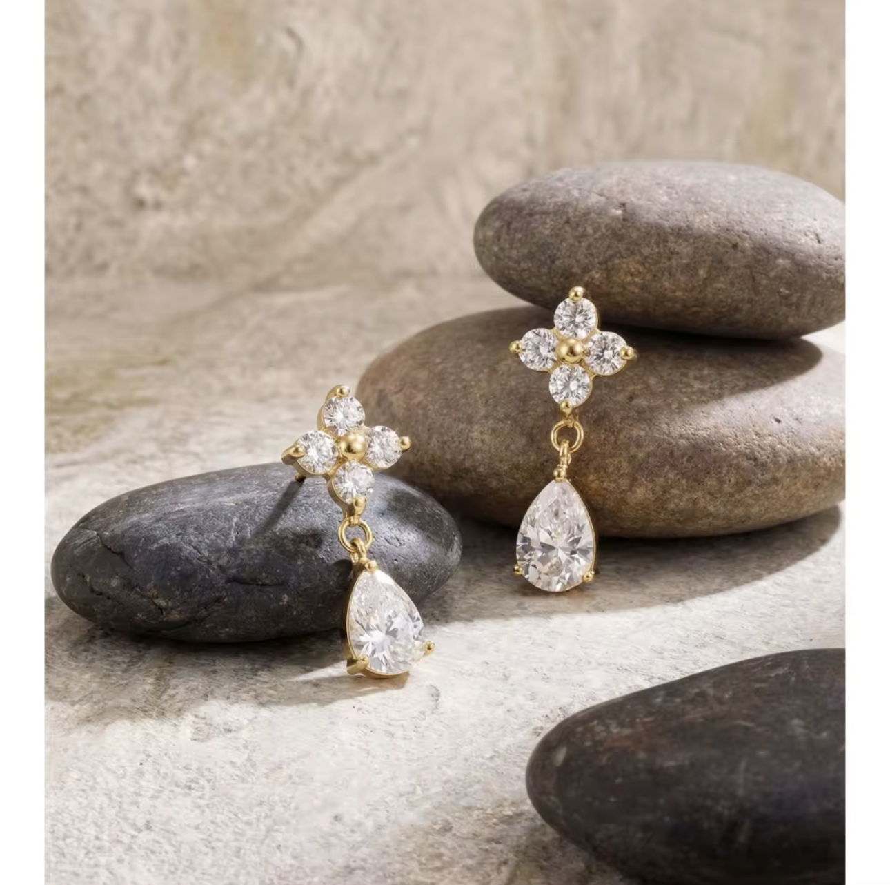 Gold and diamond earrings on stones with a neutral background