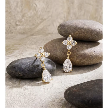 Gold and diamond earrings on stones with a neutral background