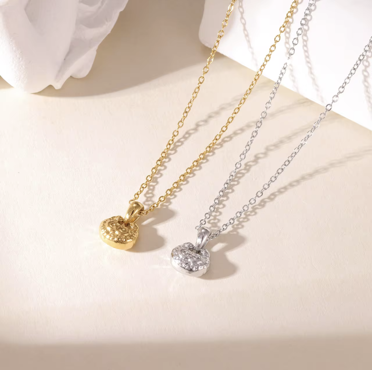 gold and silver necklace featuring small pendant with a textured engave detail pictured on a light background