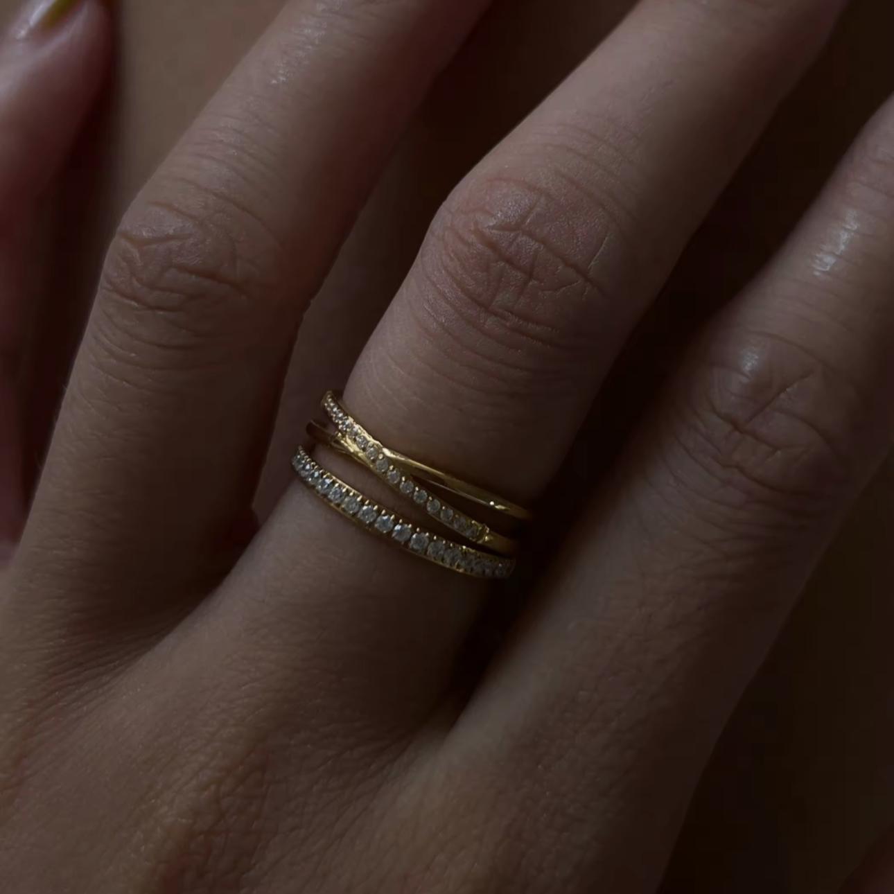 Close-up of a hand wearing two gold rings with a blurred background