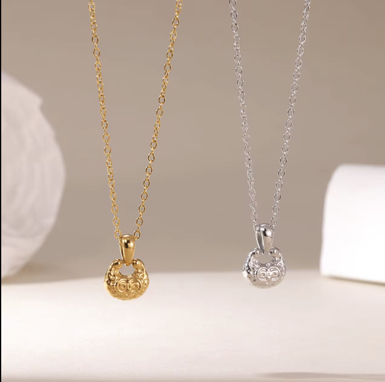 gold and silver necklace featuring small pendant with a textured engave detail pictured on a light background