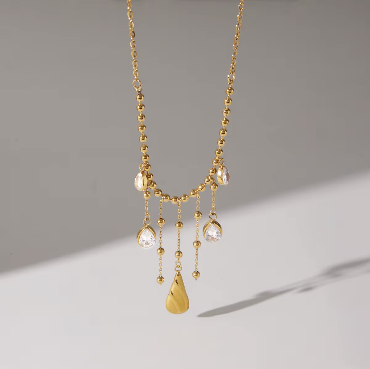 Gold necklace with hanging pendants on a gray background