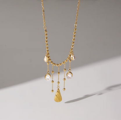 Gold necklace with hanging pendants on a gray background