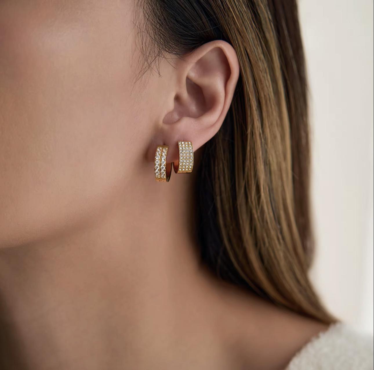 Close-up of a person wearing gold hoop earrings with a blurred background