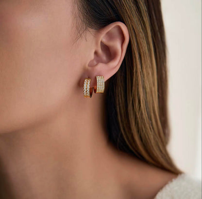 Close-up of a person wearing gold hoop earrings with a blurred background