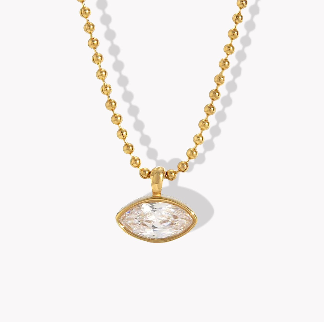 Necklace with gold beads and a clear pendant on a white background