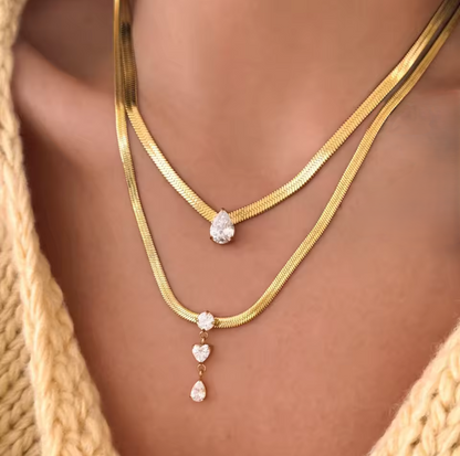 close up of 2 gold necklaces with gemstone s being worn
