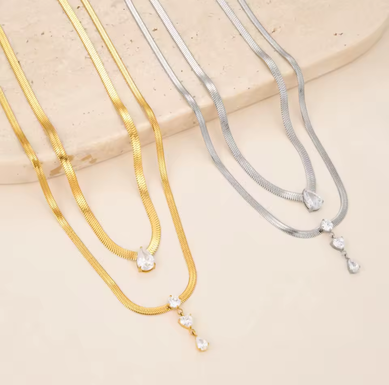 2 gold and 2 silver necklaces photographed on a beige background