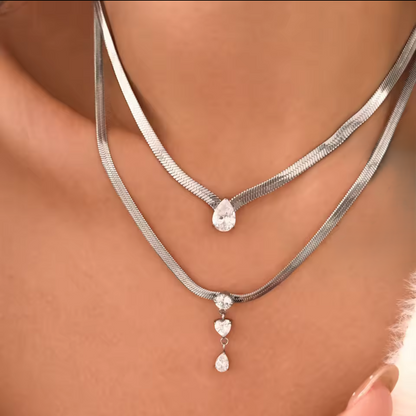 Silver necklace with heart and teardrop pendants on a person's neck