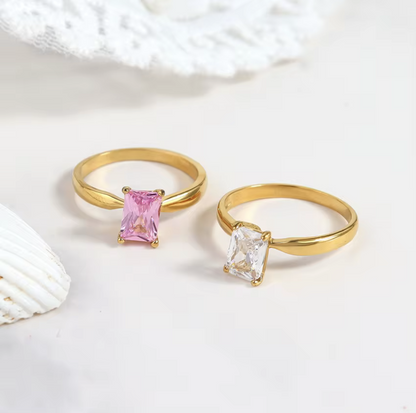 Two gold rings with gemstones on a light background