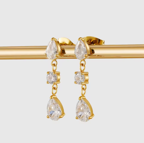 Gold earrings with clear gemstones on a light gray background