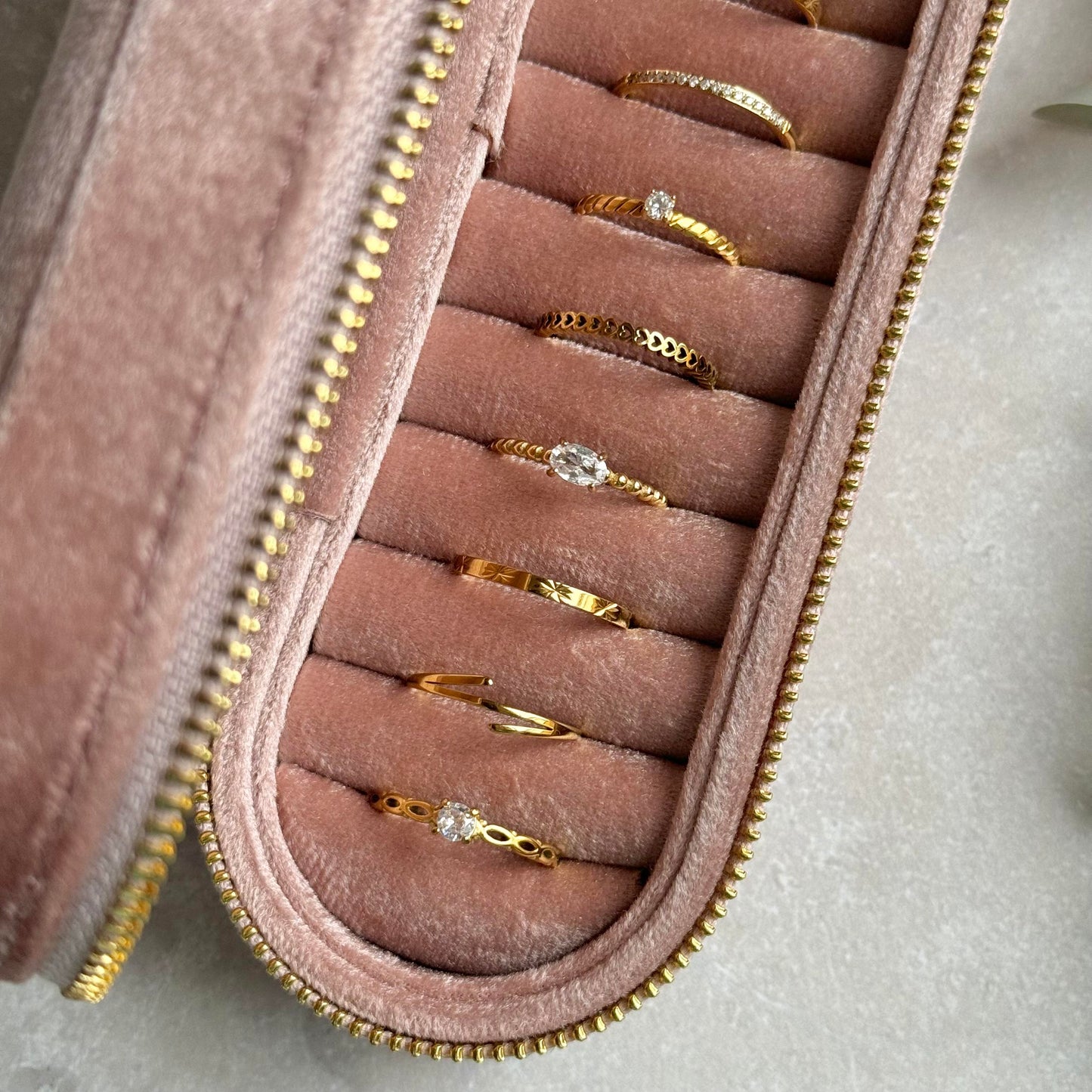 Dusky Pink jewelry case with gold rings on a light grey background