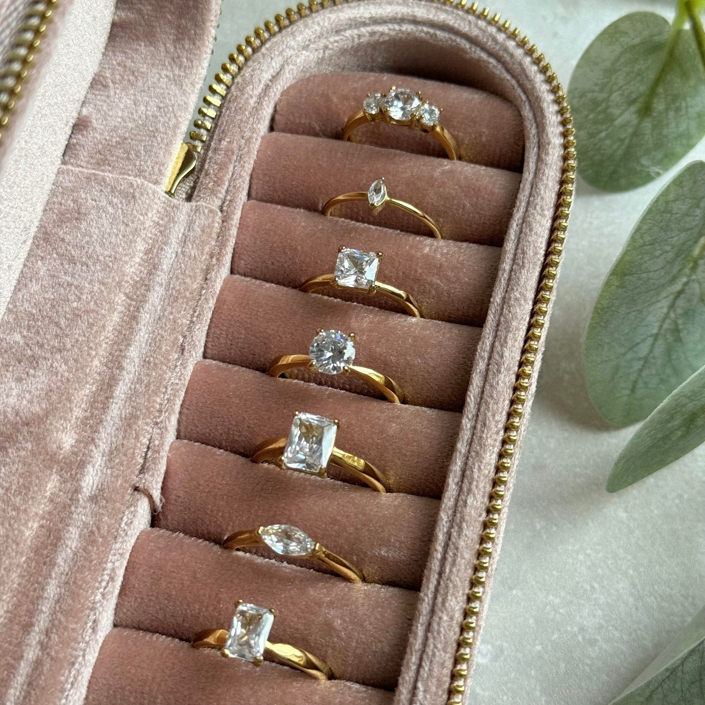 Set of gold rings with diamond stones in a pink jewelry case.