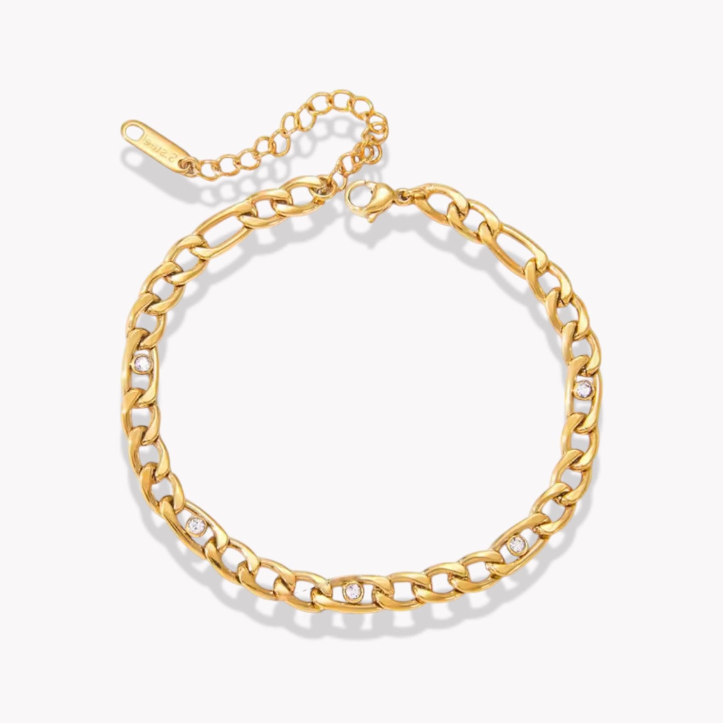 Gold figaro style chain bracelet with small clear gemstone detail on a white background