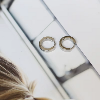 Gold hoop earrings on a reflective surface with a blurred background