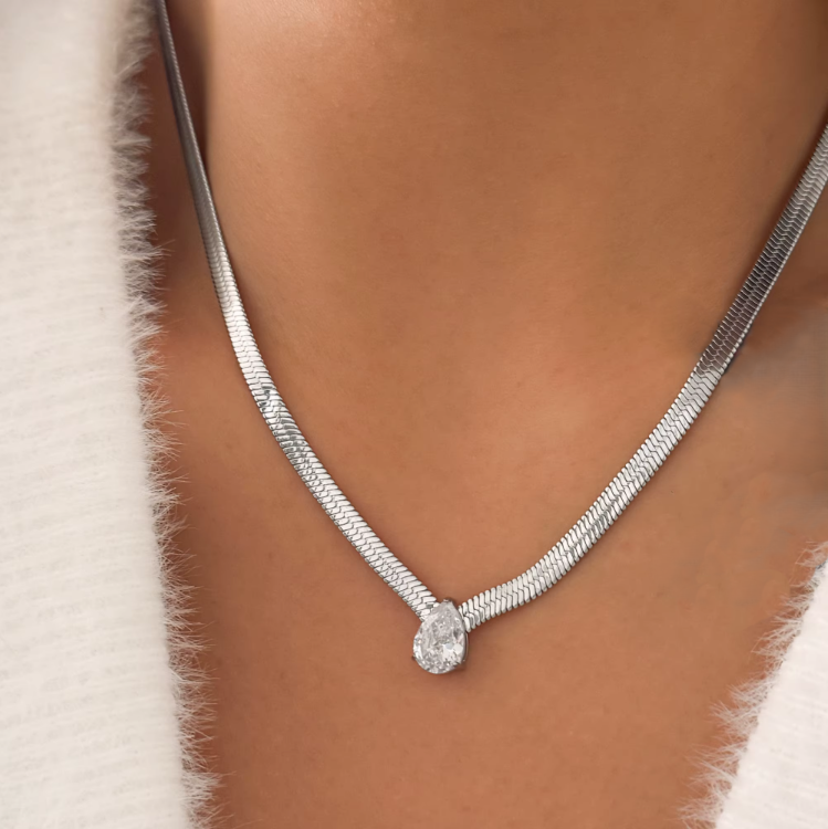 silver necklaces with a pear pendant. layered on a persons neck