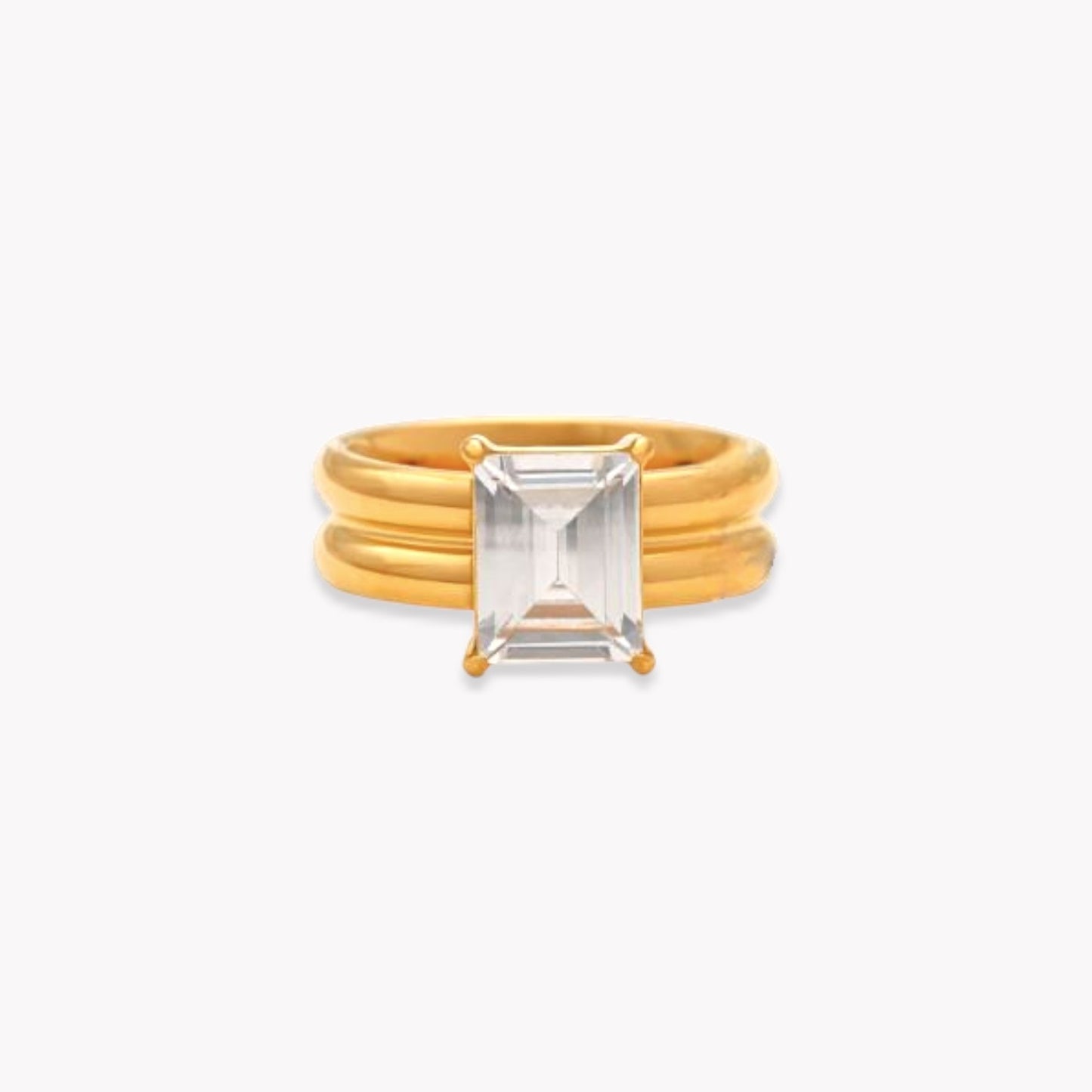 Gold ring with a thicker band and large rectangular gemstone on a white background